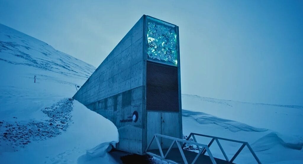 Estrutura de concreto em montanha nevada com janela iluminada exibindo cristais preservados banco do juízo final cofre de sementes na Noruega