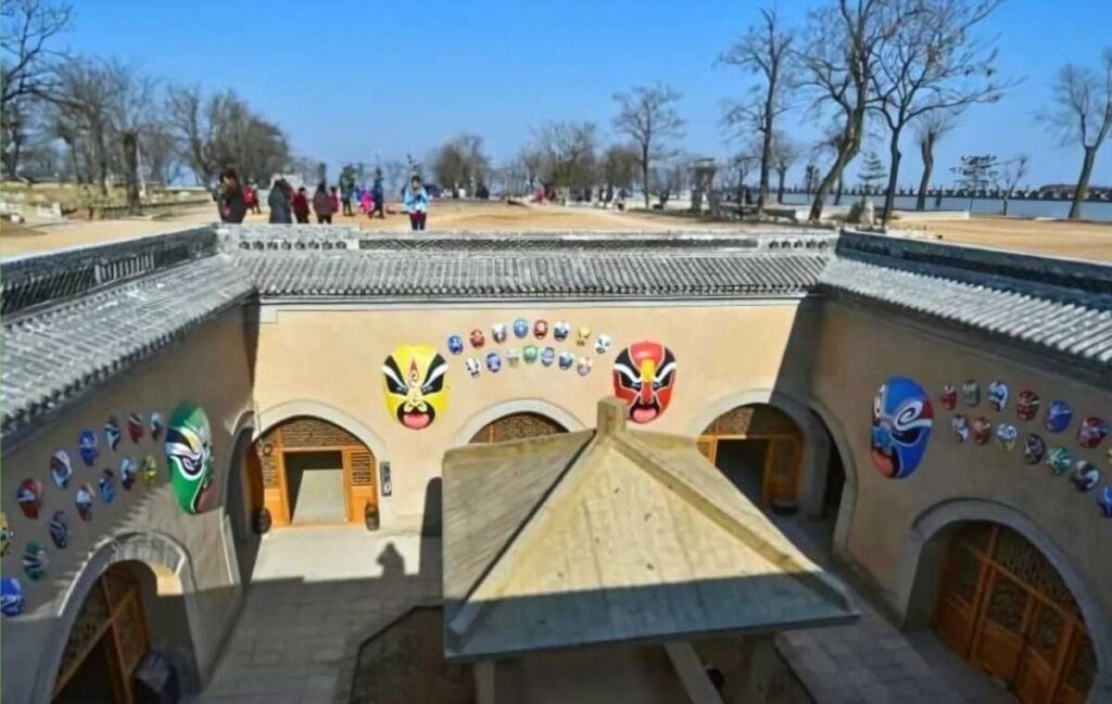 china cidade em baixo da terra Pátio com casa tradicional decorada com máscaras coloridas e arcos contra céu azul e árvores secas Cidades debaixo da terra