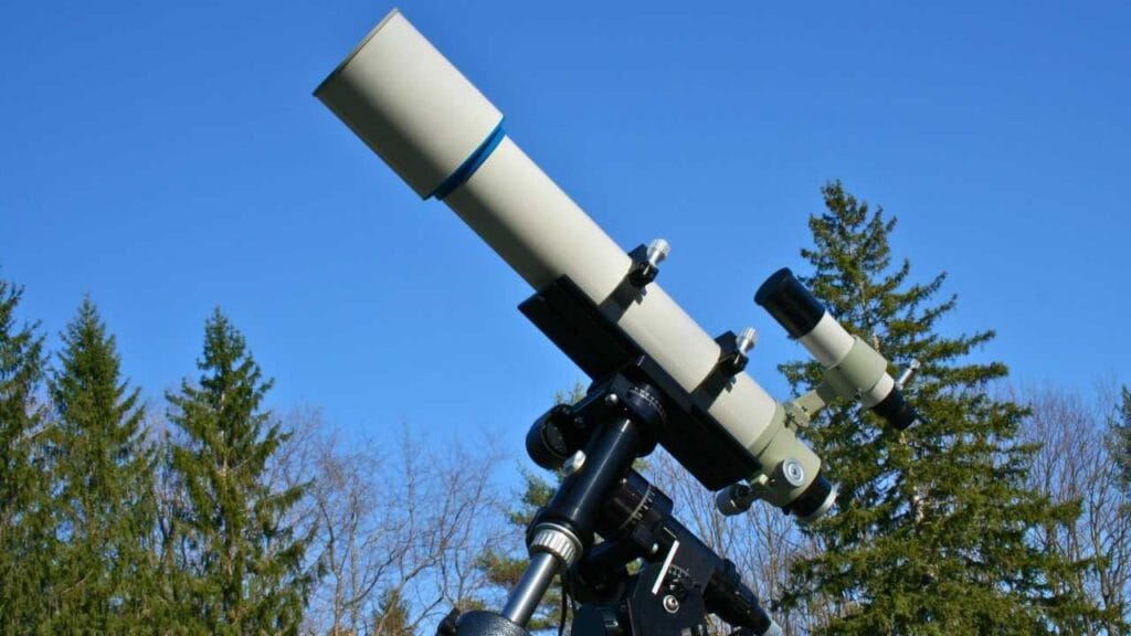 Telescópio apontado ao céu azul em dia claro ideal para observação astronômica e exploração do espaço durante o dia Tipos de telescópios