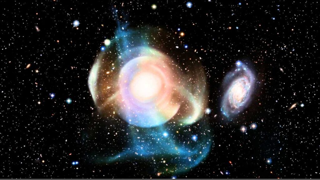 Visão telescópica realista da galáxia elíptica NGC 474 no espaço profundo, destacando suas complexas camadas e conchas gasosas em tons de azul e roxo ao redor do núcleo brilhante, com uma galáxia espiral menor à direita e um fundo repleto de estrelas. Imagem GPT/ Planeta